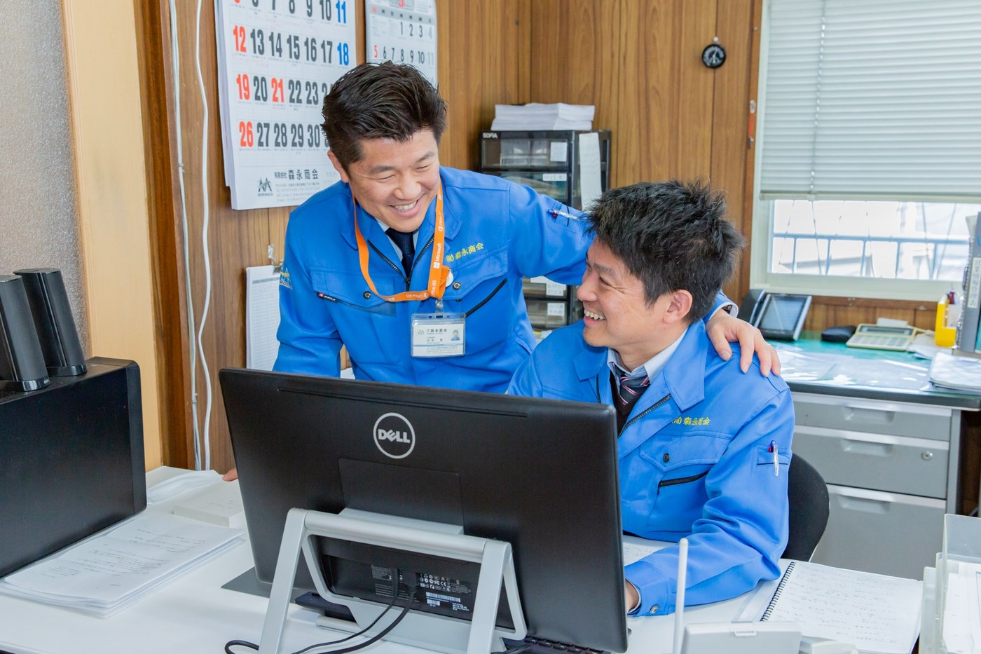 有限会社森永商会のオフィスで、スタッフが連携しながら業務を進める様子