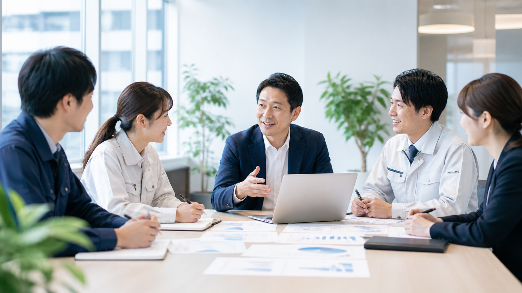 経営者と現場メンバーが会議室でPCや資料を見ながら前向きに相談している様子